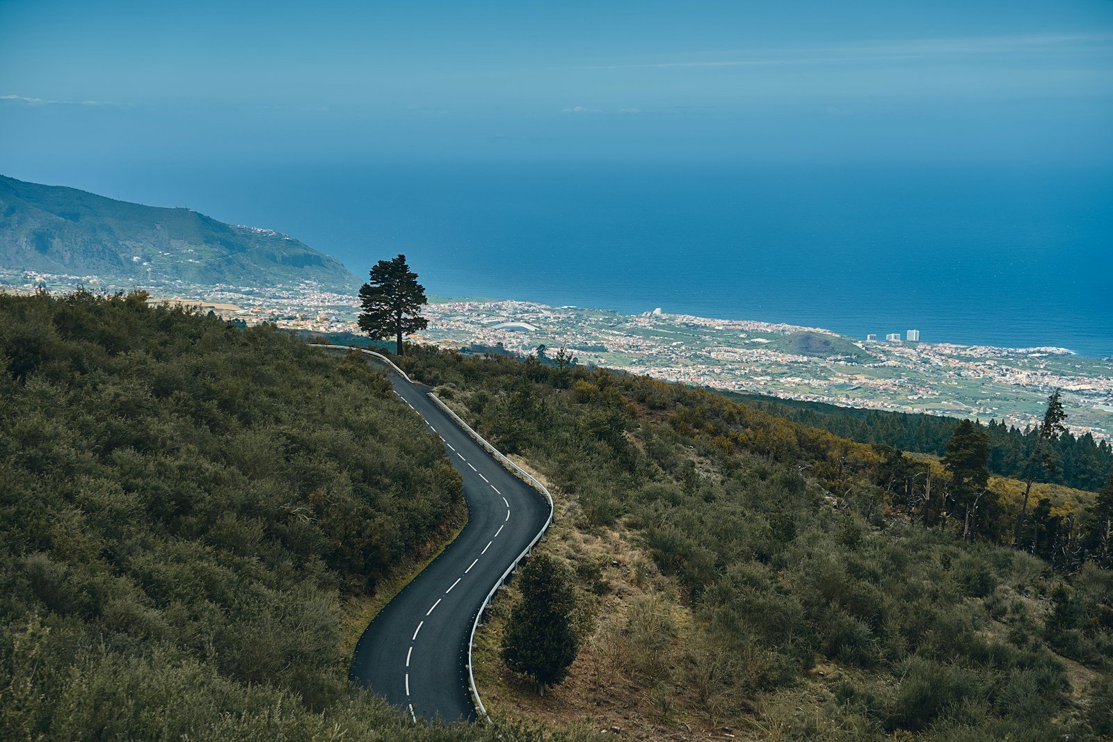 Carretera estrecha de montaña sin arcén que asciende hacia un núcleo serrano